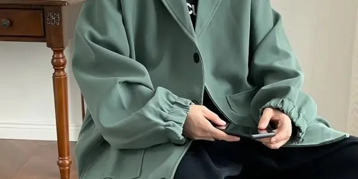 Mann trägt grünen Oversize-Blazer mit lockerem Schnitt, kombiniert mit schwarzem T-Shirt und schwarzen Hosen, moderner Oversize-Look für Herren.